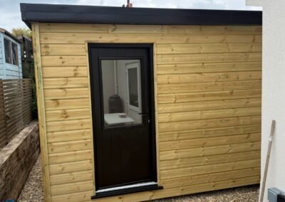 Front view of bespoke garden room with black composite door and timber cladding by KAP Woodwork and Building