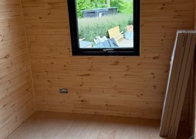 Interior of bespoke garden room showing pine tongue-and-groove lining and black-framed window by KAP Woodwork and Building